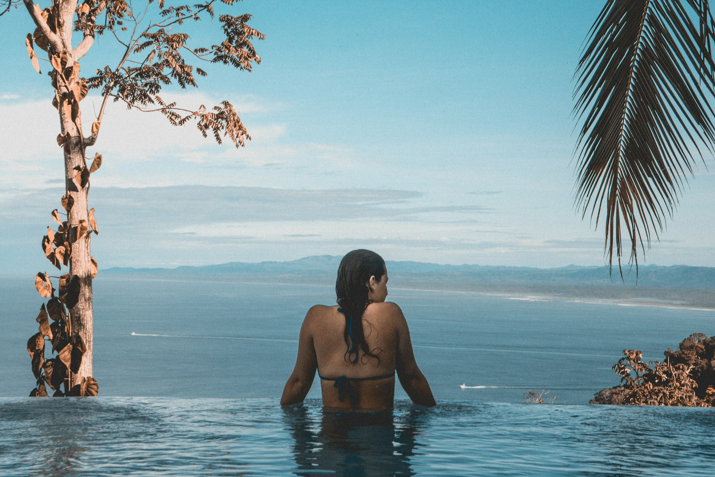 A woman enjoying a beautiful beach in Costa Rica, representing the potential for remote travel agents to earn well and enjoy travel perks