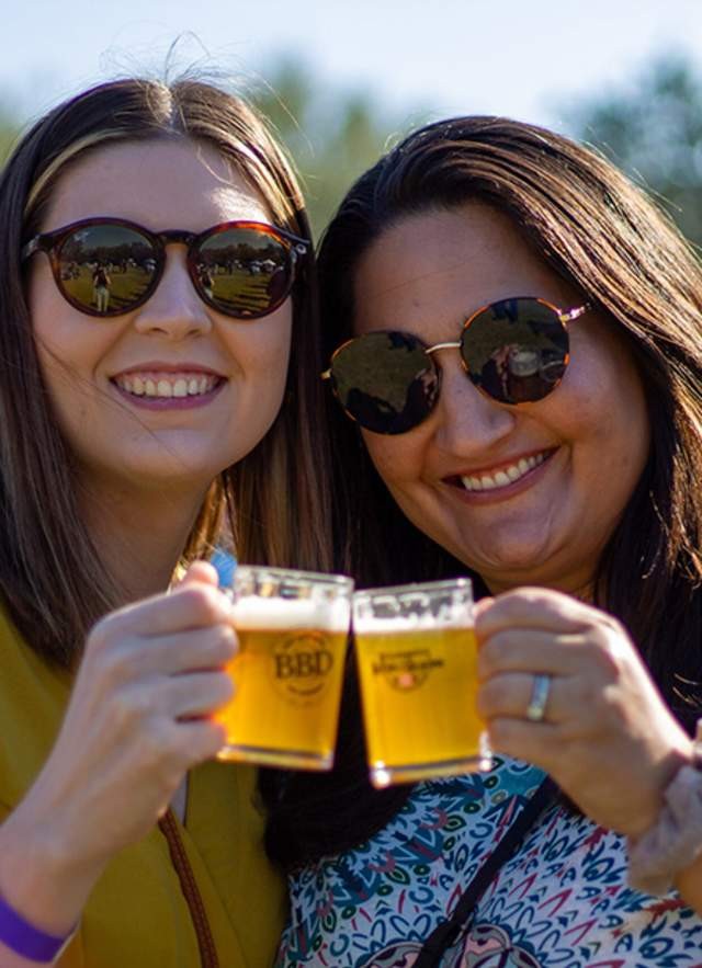 Two friends raising their mugs in a beer toast in a casual environment