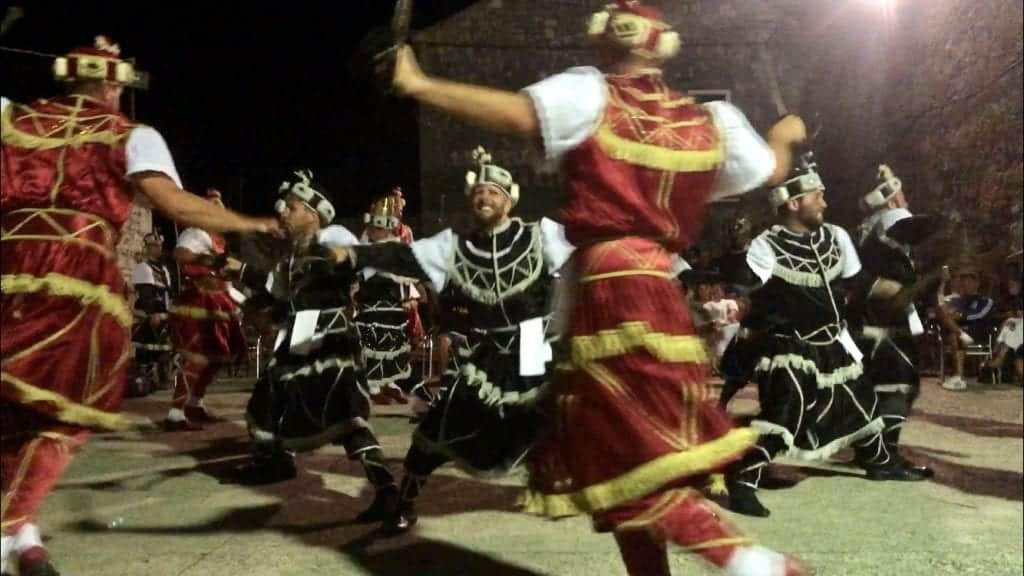 Men in red and black medieval costumes doing a sword dance