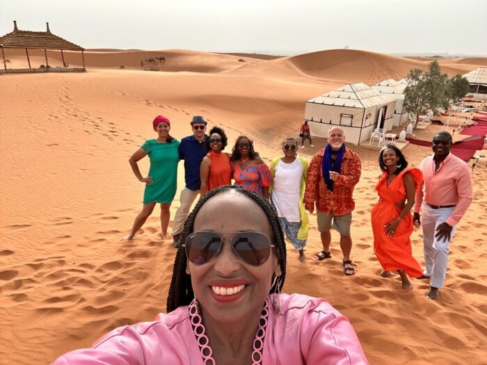 Group photo at a glamping site in Merzouga, capturing the colorful attire and joyful experience of desert glamping