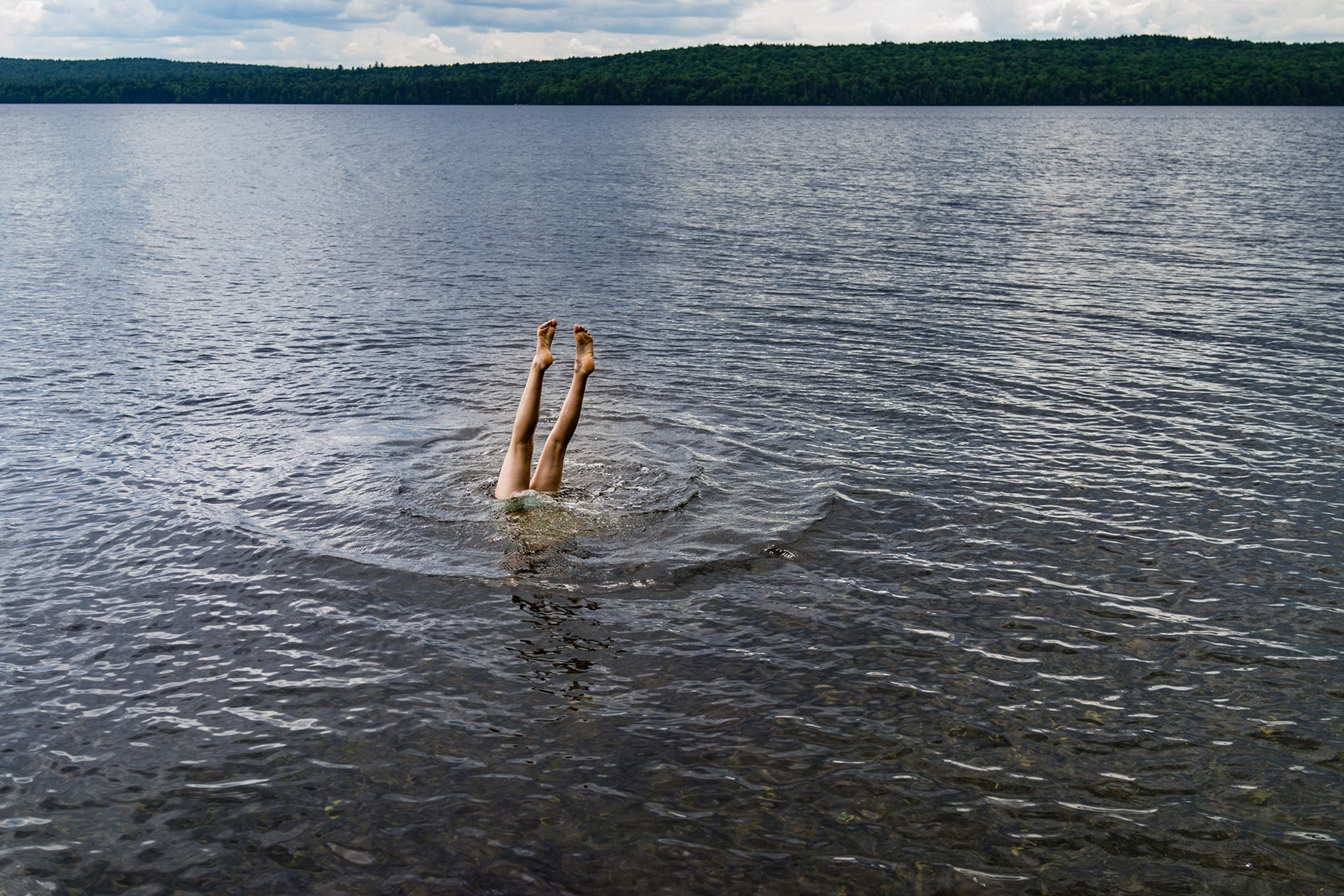 A teenage girl does a handstand in Moosehead lake