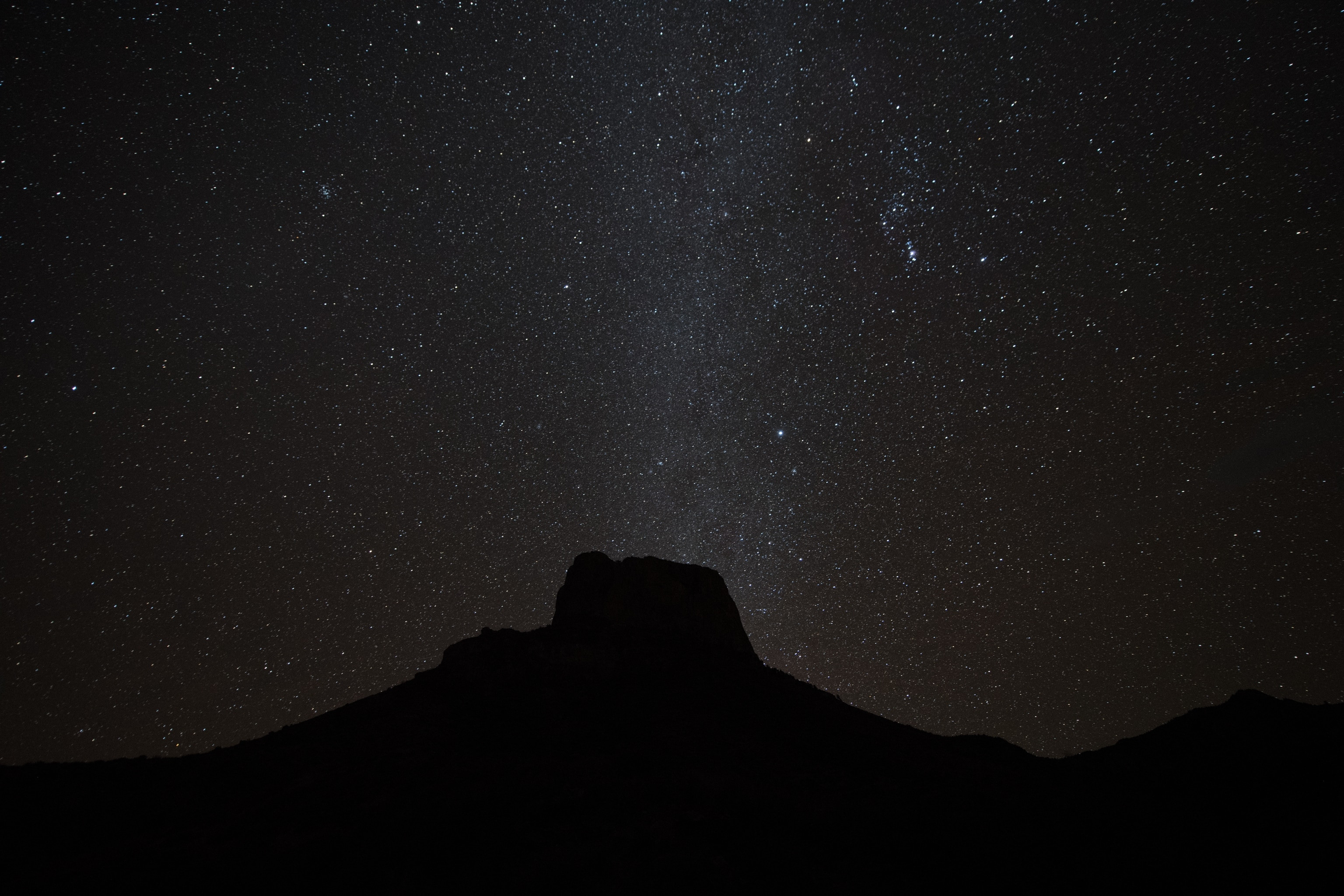 Stars shine behind the silhouette of the Chisos Mountains in Big Bend National Park, Texas, USA