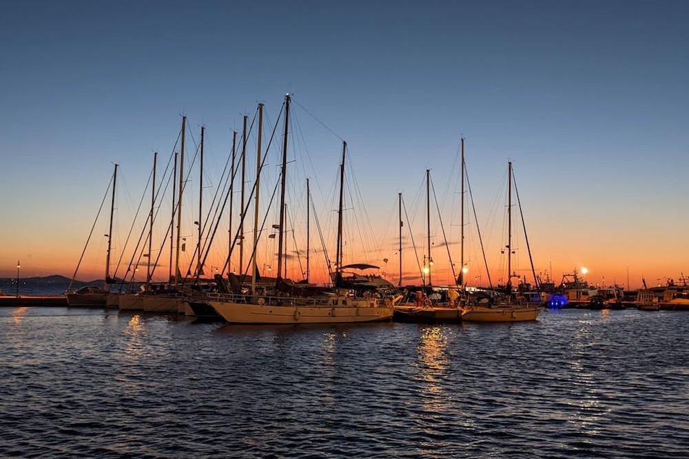 Sunset over sailboats in Naxos, Greece, capturing the serene autumn atmosphere with fewer crowds and inviting weather.