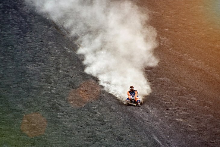 A person volcano surfing down the black ash of Cerro Negro with protective gear