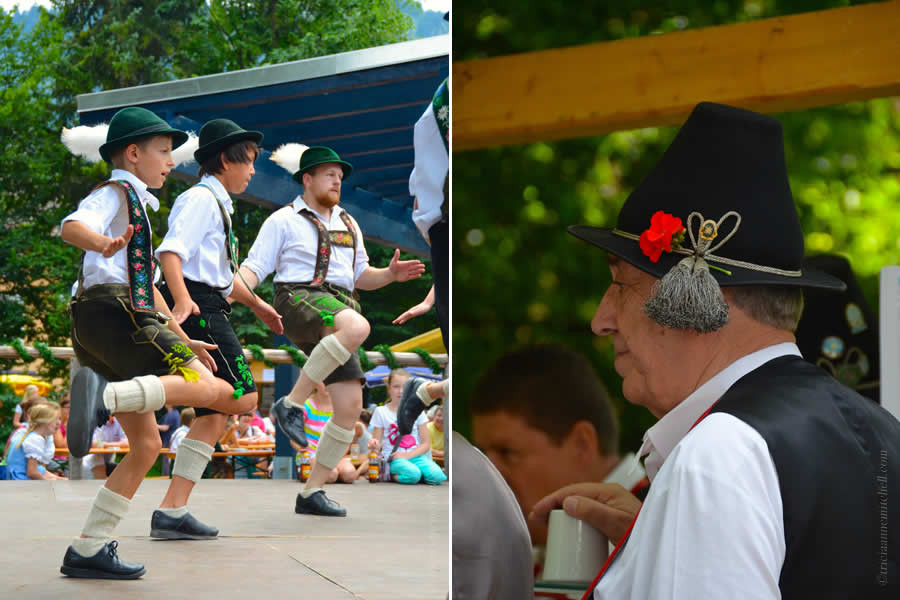 Two boys and an adult male perform a traditional dance in Oberammergau, Germany in the picture on the left. They are wearing green hats with a white feather. They appear to be slapping their feet, while lifting their knees. On the right, a close-up of a man wearing a Bavarian black hat, with grey tassels and a red flower.
