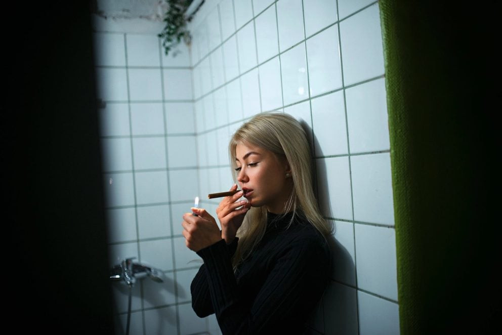 A woman in black long sleeve shirt smoking a cigarette
