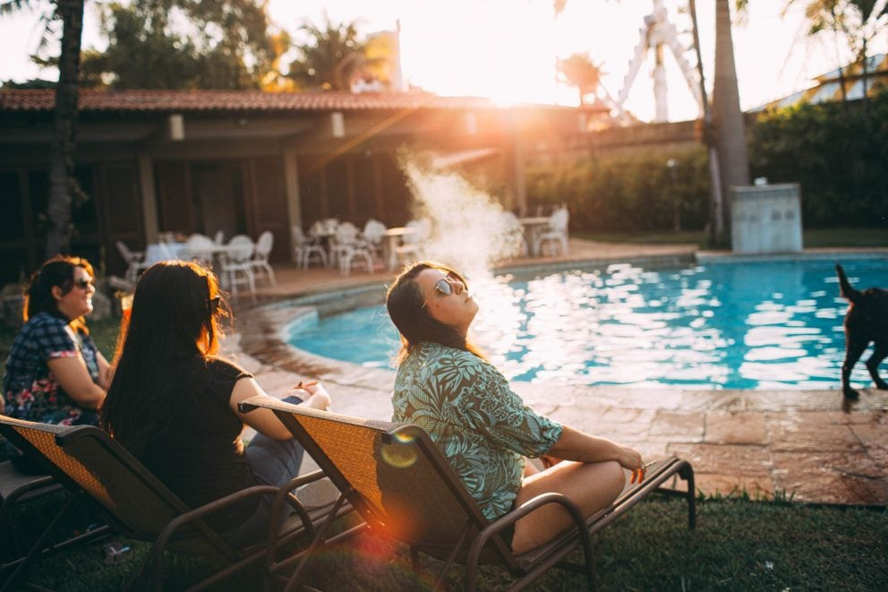 Young woman smoking while resting on poolside