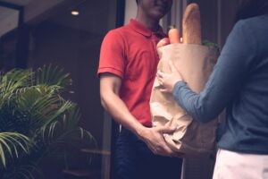 a person receiving a meal delivery at their doorstep. Alt text: Meal delivery for travelers, Vietnam service
