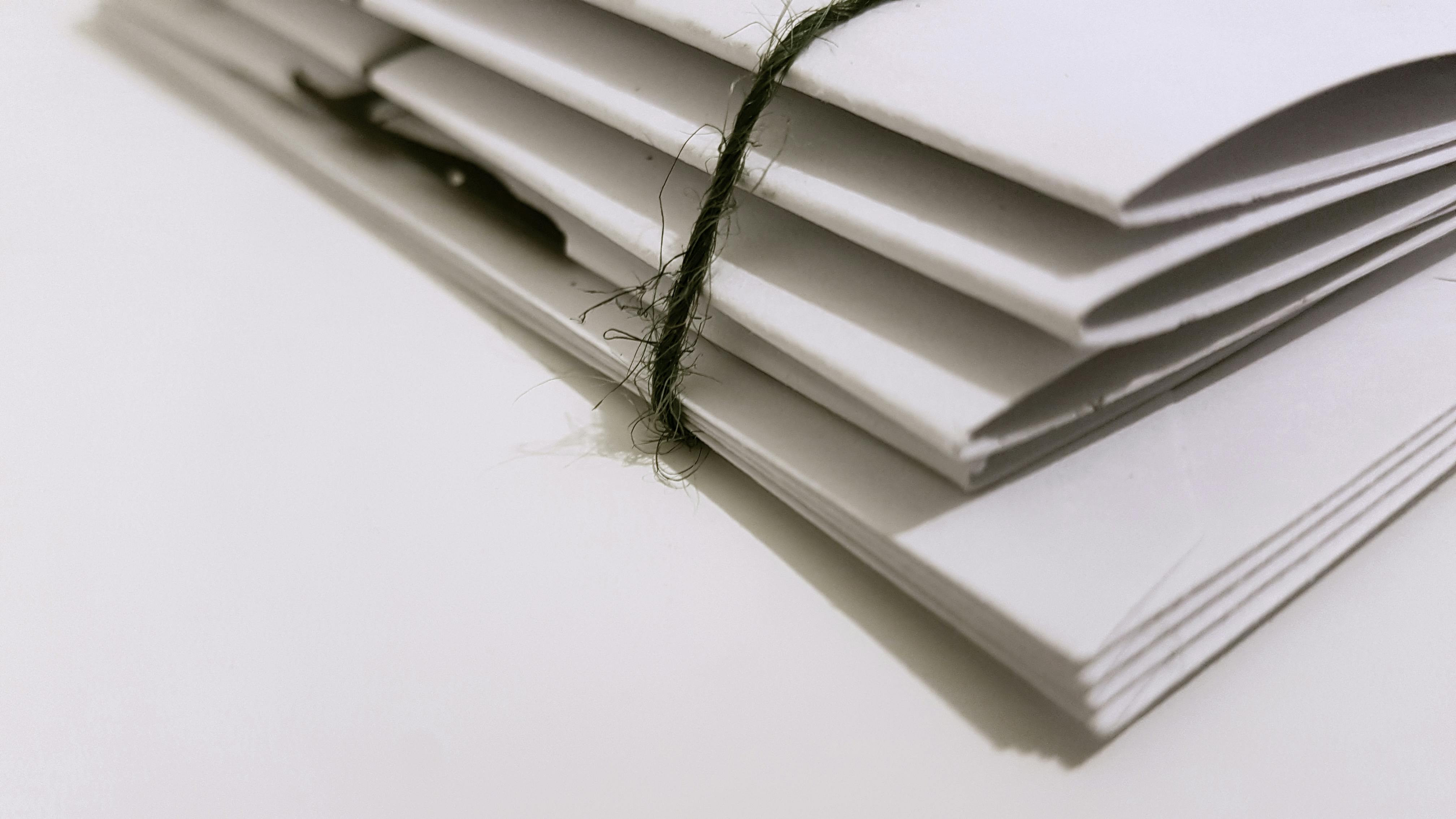 A stack of white envelopes tied together with a rough string, placed on a plain surface, symbolizing mail or confidential documents, representing the correspondence involved in the ETIAS application process.
