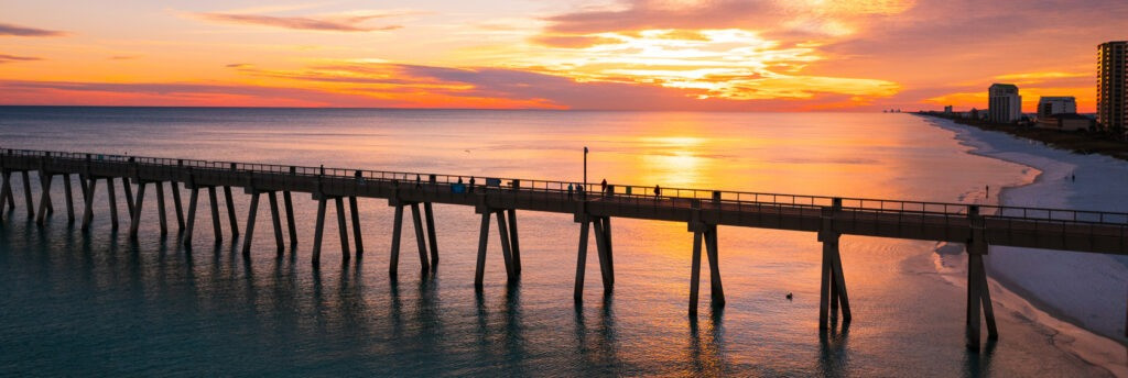 Navarre Beach Pier at sunset, showcasing a picturesque view of the coastline and sky
