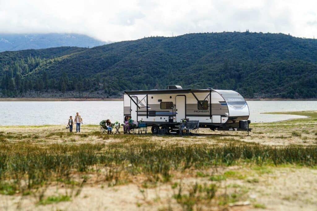 Heartland Pioneer travel trailer set up near a lake.