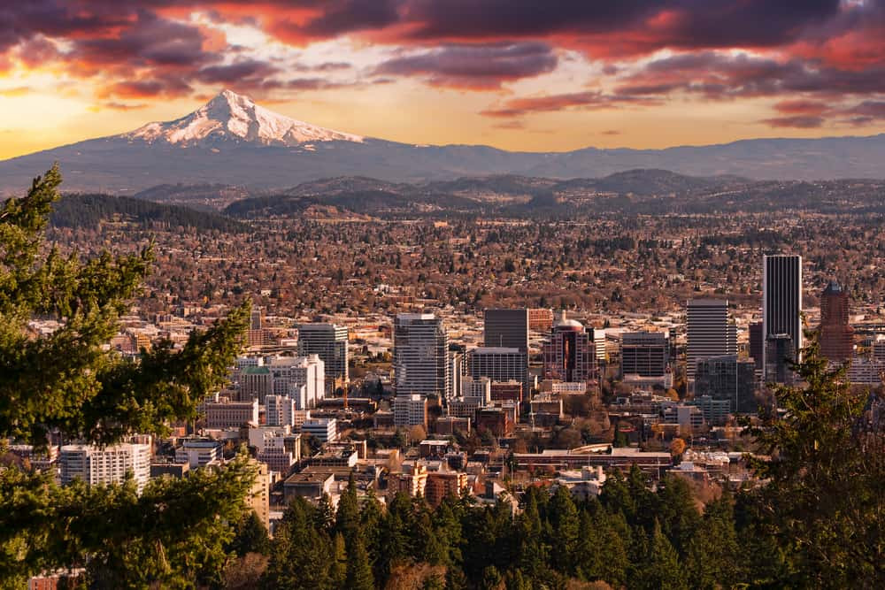 A vibrant street scene in Portland, Oregon, showcasing a mix of modern and historic buildings with people enjoying the summer weather