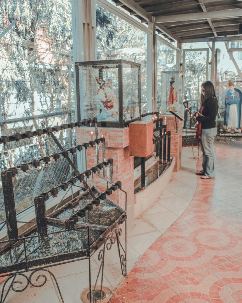 Visitor praying inside the serene Baguio Cathedral, surrounded by religious art and architecture
