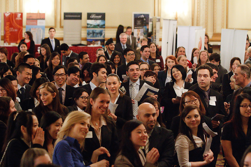 A crowd of students dressed in business clothes. Many hold folders