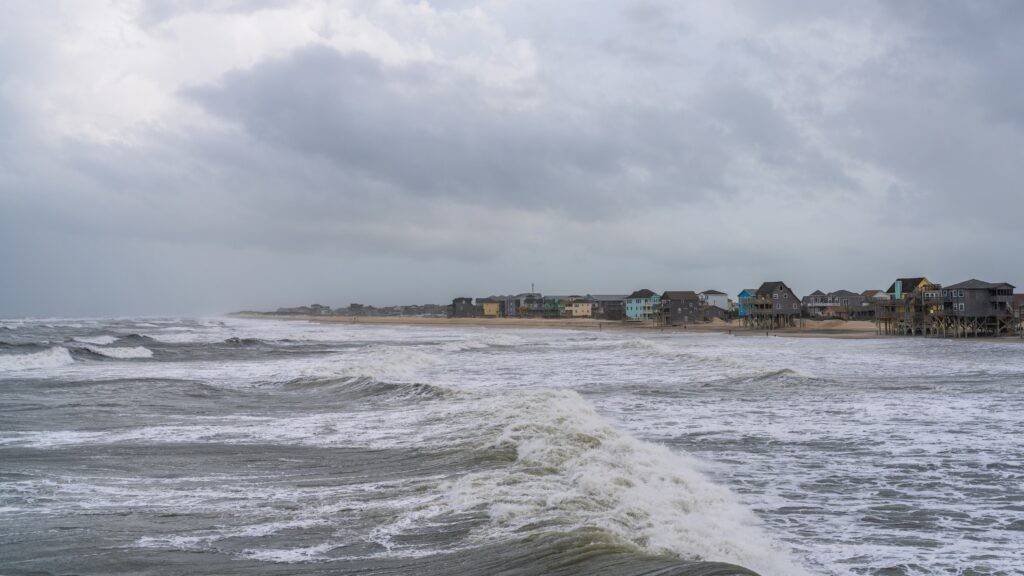 Coastal erosion threatening a beach resort, illustrating the impact of rising sea levels on tourism destinations.