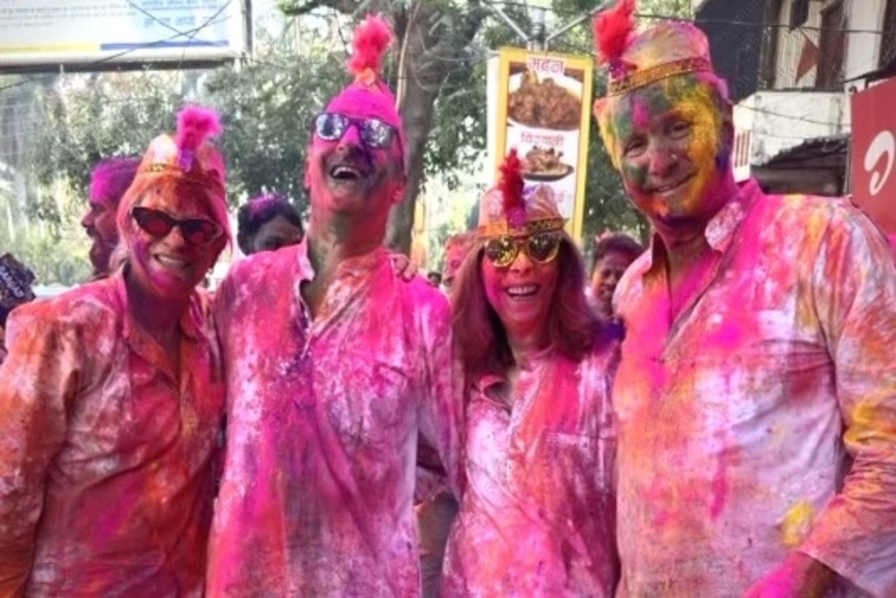 Travelers enjoying the Holi festival in India, covered in vibrant colors.
