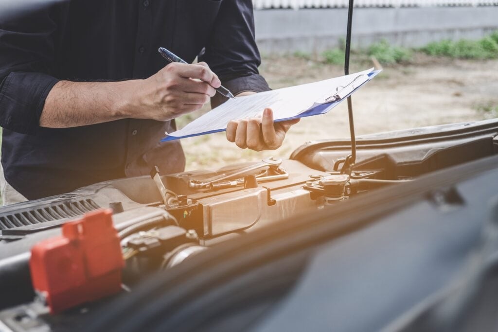 RV inspector leaning over the engine of an RV with a checklist in hand