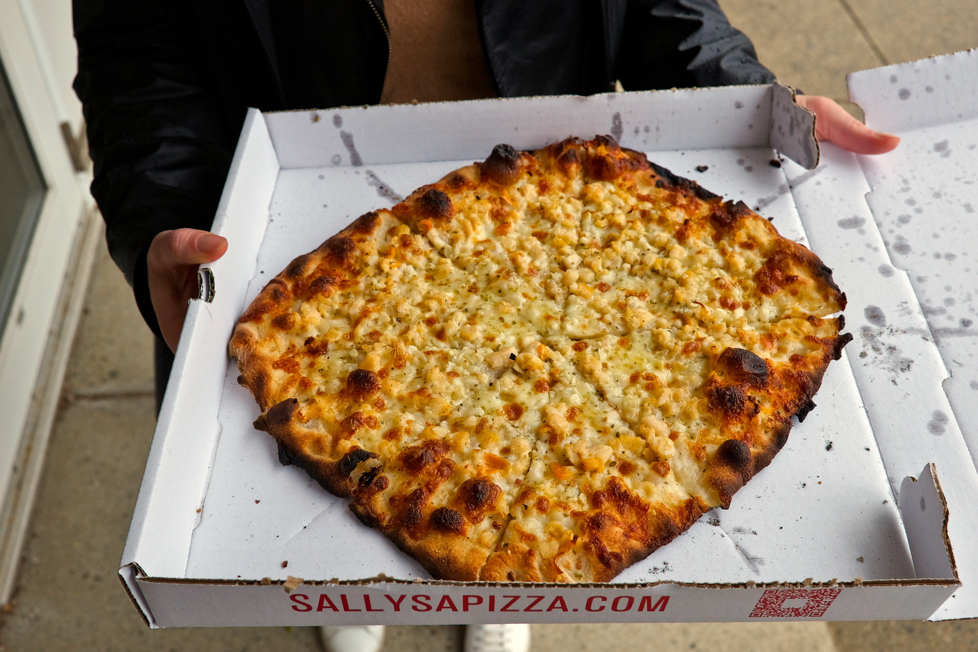 Alyssa holds a pizza from Sally