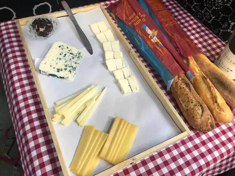 Sampling cheese and baguettes on our Paris Secret Food Tour. Alt Text: Tourists sampling cheese and baguettes on a food tour in Paris, enjoying local culinary delights