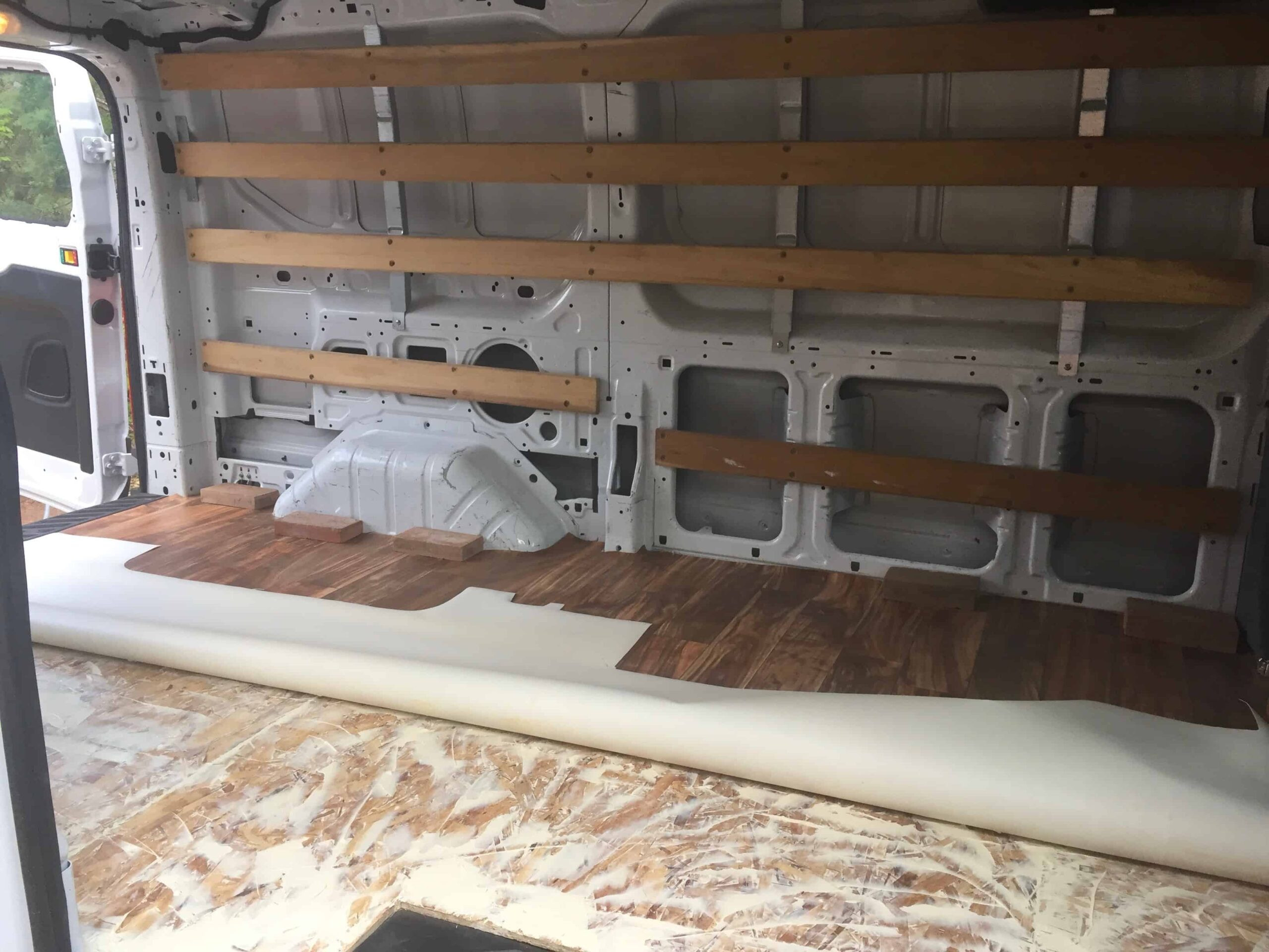 Securing a vinyl floor with bricks in a DIY van conversion