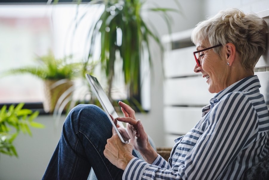 Happy woman reading tourism newsletter on tablet, illustrating customer engagement.