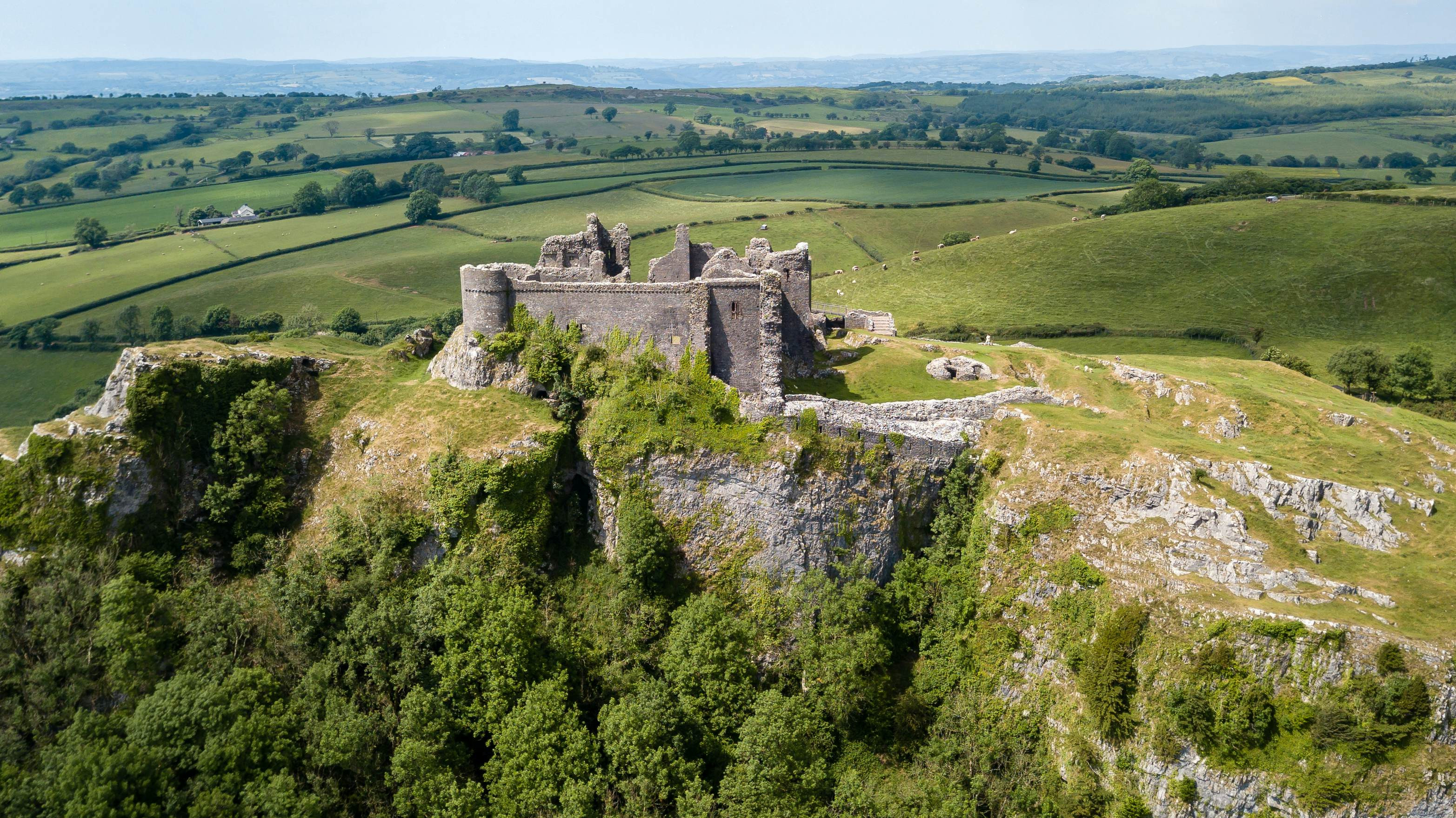 Aerial view of the ruins of an ancient castle on a hilltop on a sunny day.