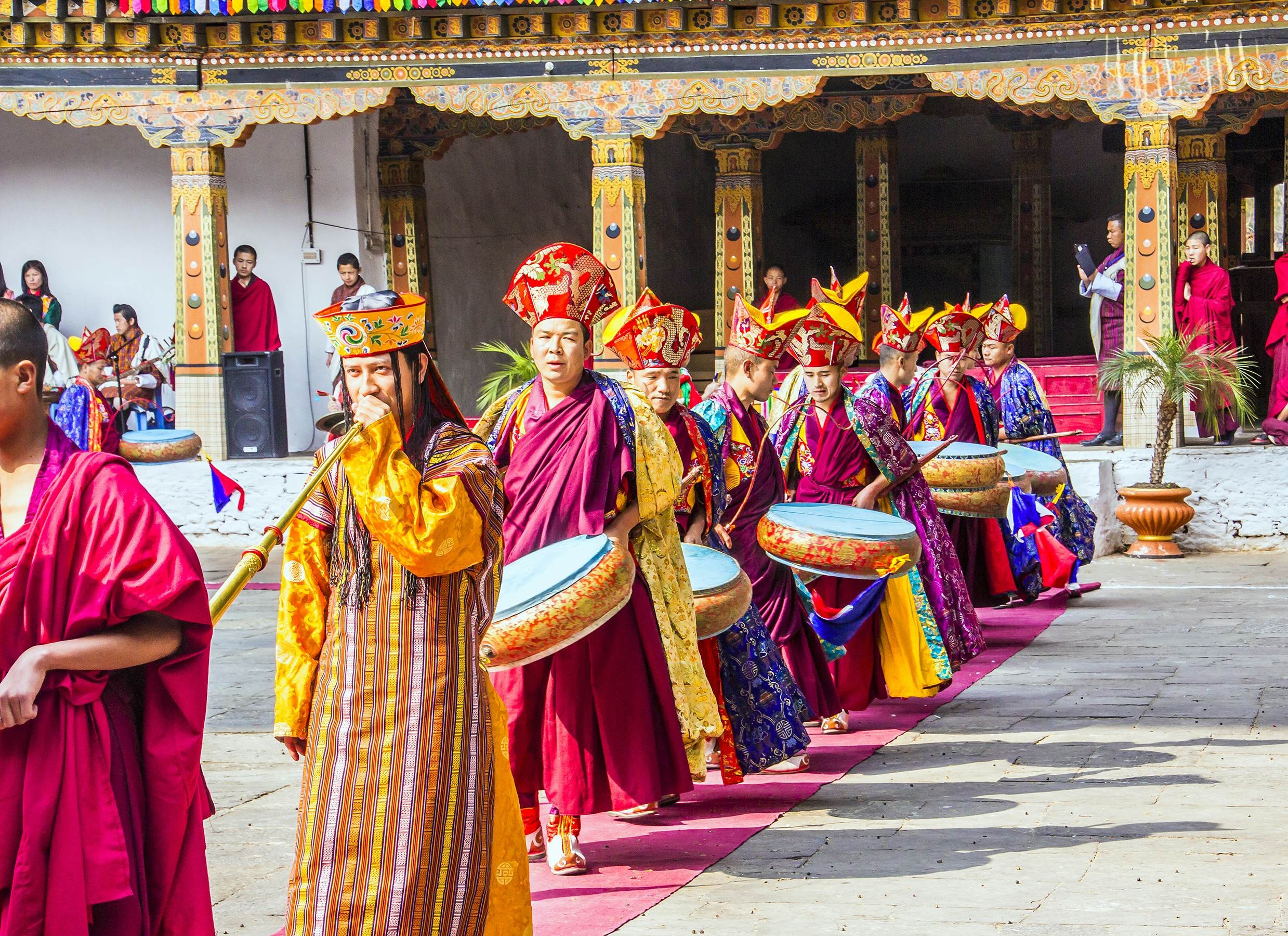 Dancers wearing traditional costumes and carrying drums and horns form a procession at a festival