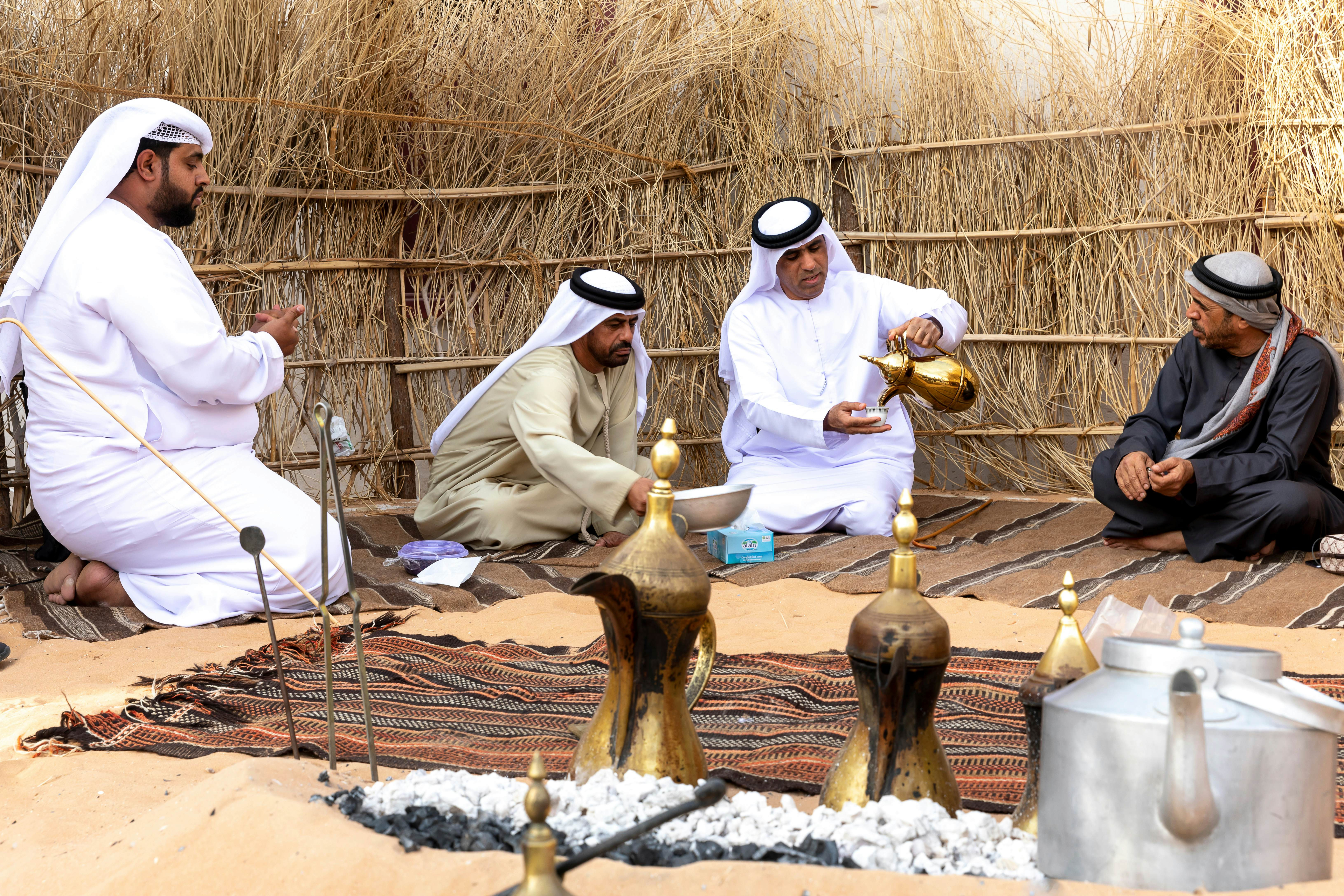 Arabic men drinking coffee inside a traditional Bedouin tent.