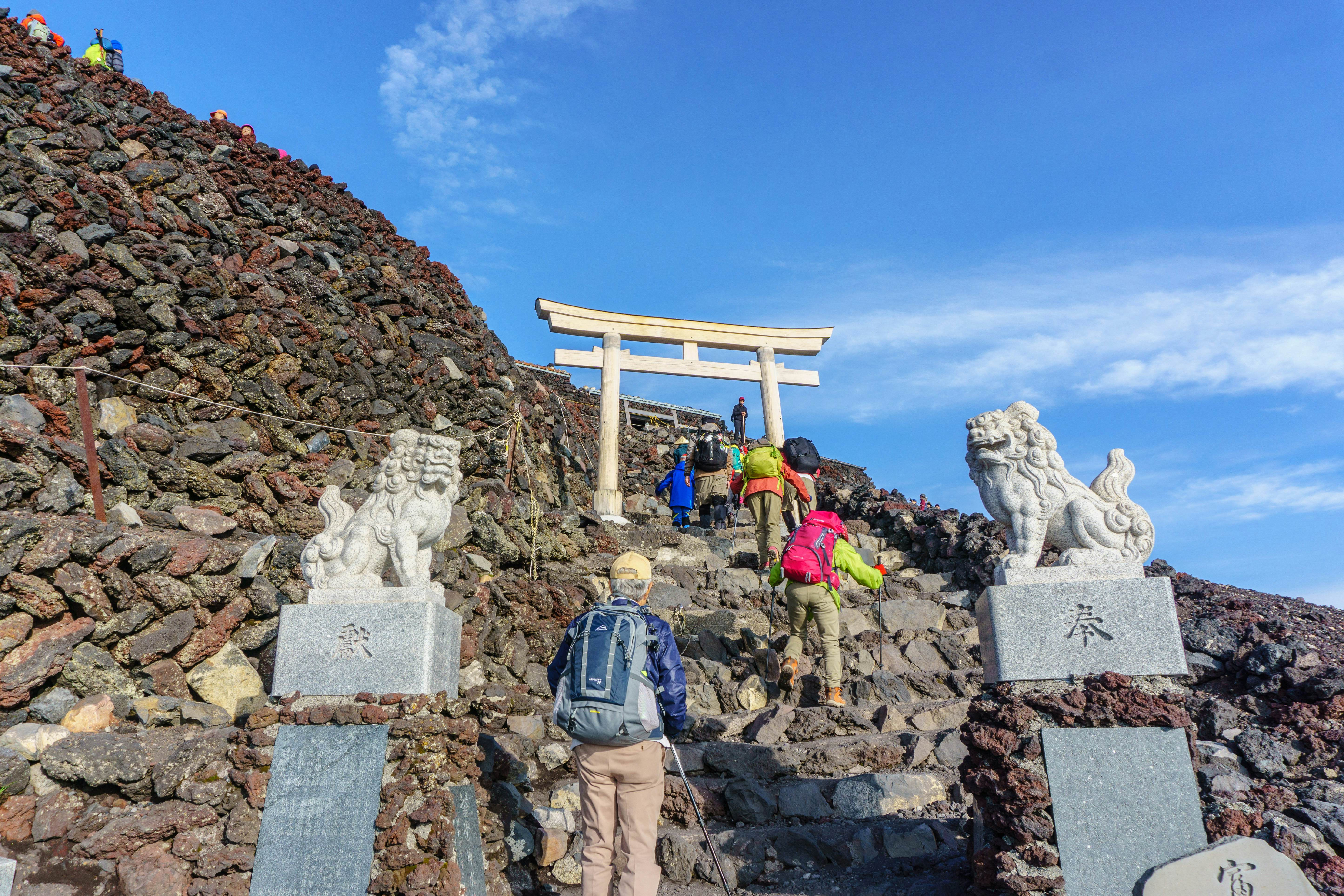 Hikers ascend steps towards a torii gate