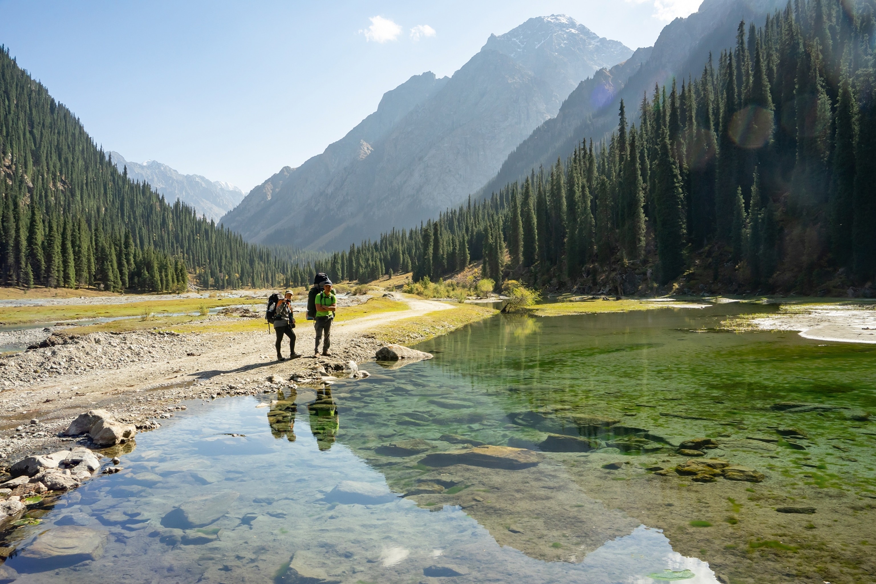 Two hikers by a lake on the Ala-Kul trek in Kyrgyzstan.