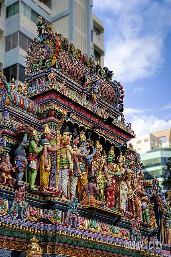 Tourists stroll along a Singapore street, showcasing the vibrant cultural diversity with temples and modern buildings in the background.