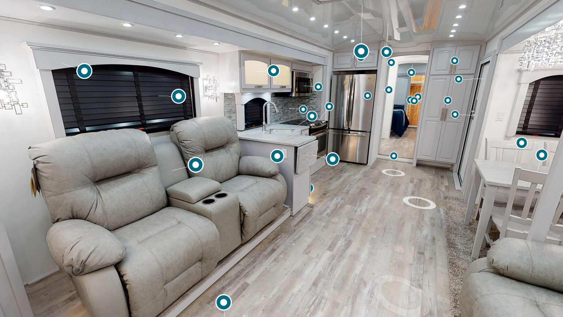 Spacious interior of a long Space Craft semi travel trailer, featuring a fully equipped kitchen with stainless steel appliances and mosaic backsplash.