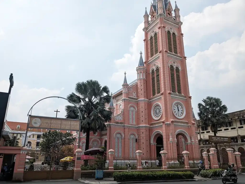 The pink Tan Dinh Church in District 3, Ho Chi Minh City, showing motorbikes driving by on a sunny day in Vietnam