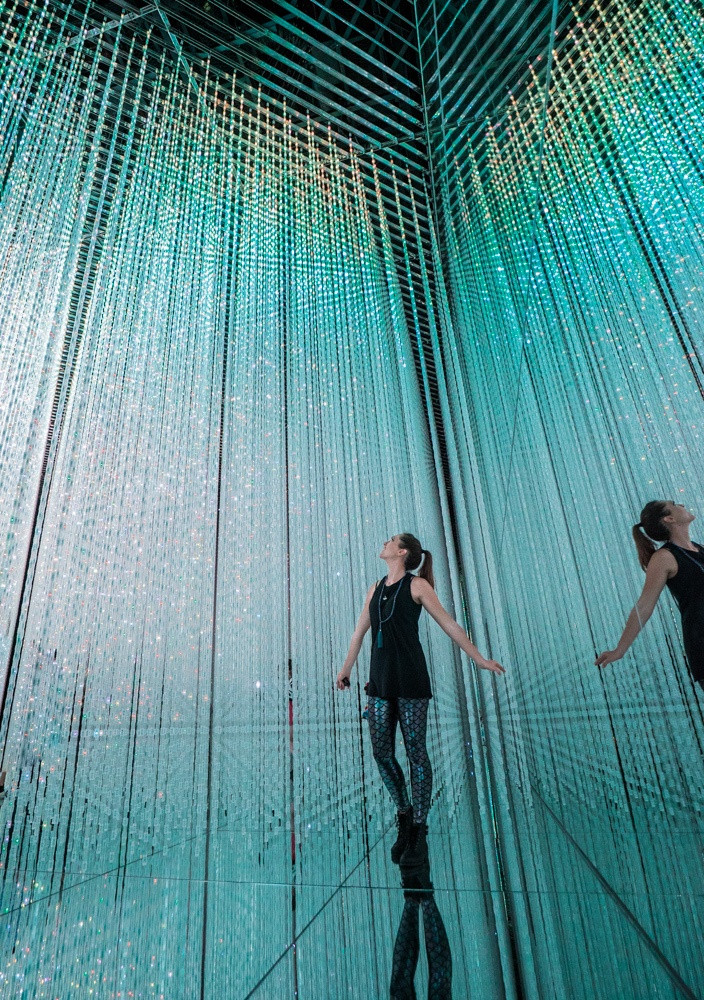 Woman standing in a museum in Tokyo, Japan, observing digital art