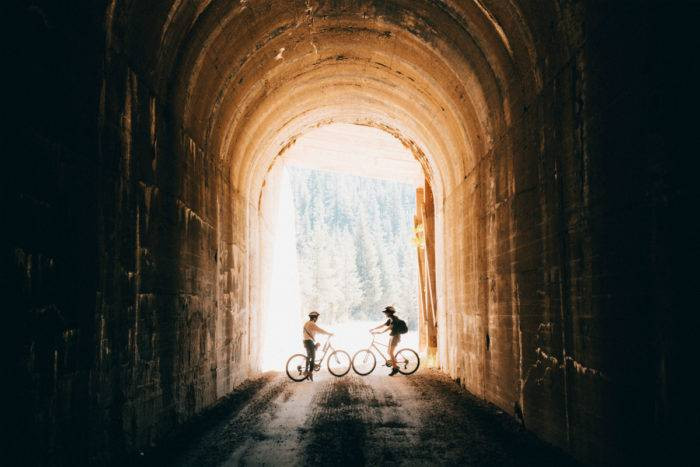 Two bike riders in a tunnel on the Route of the Hiawatha, Northern Idaho.
