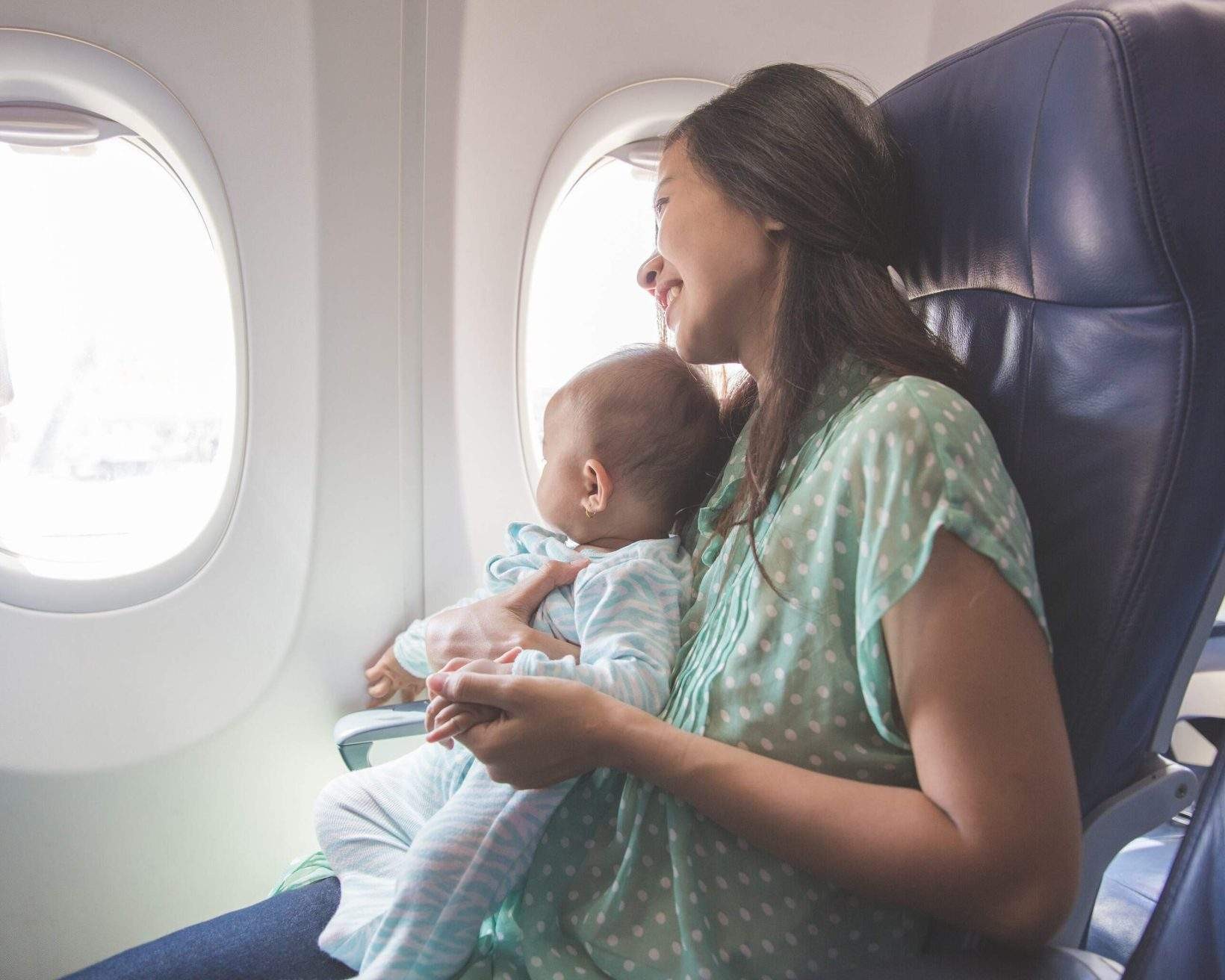 A mother and baby seated on an airplane, emphasizing the need for proper travel documentation.