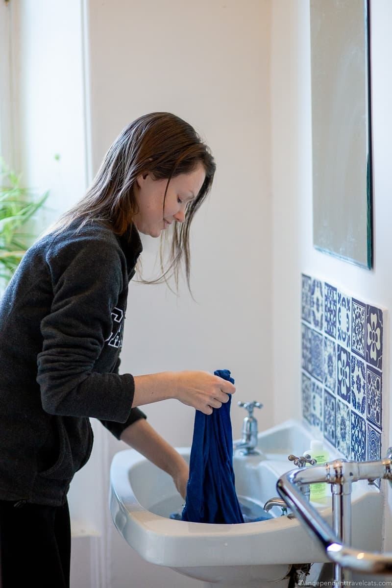 Hand washing in a sink during travel, demonstrating essential travel laundry tips
