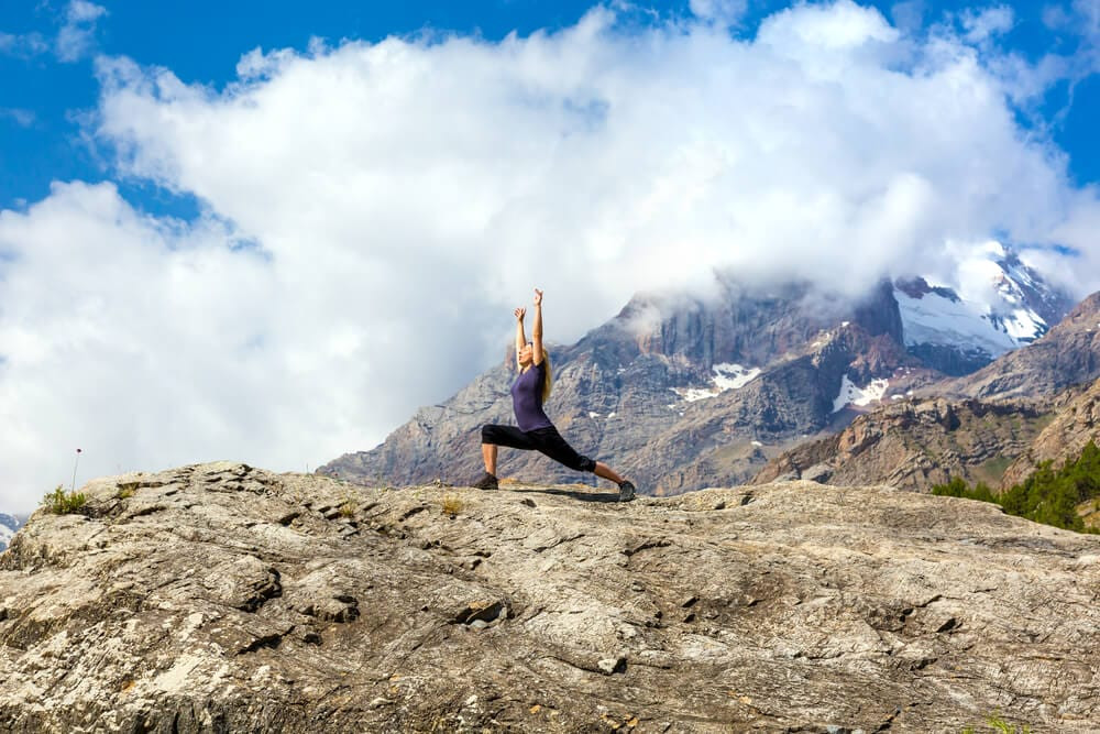 Woman doing yoga on a travel yoga mat in a mountainous region