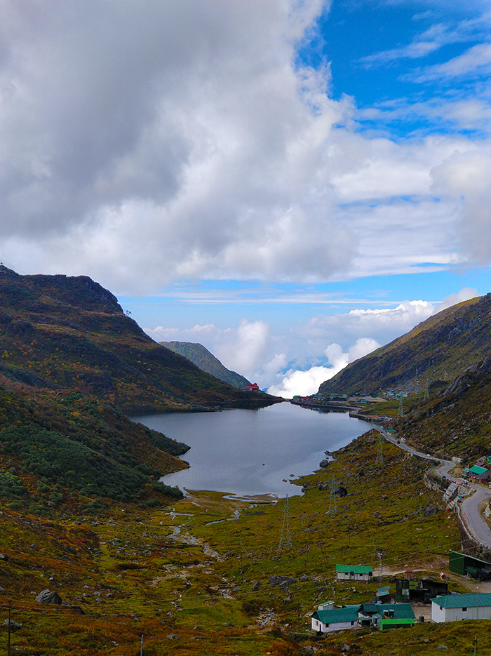 Tsomgo Lake Alt Text: Serene Tsomgo Lake in Sikkim, featuring its pristine waters reflecting the surrounding mountains and sky, offering a tranquil and picturesque experience for tourists.