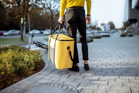 Man in yellow t-shirt carrying thermal bag