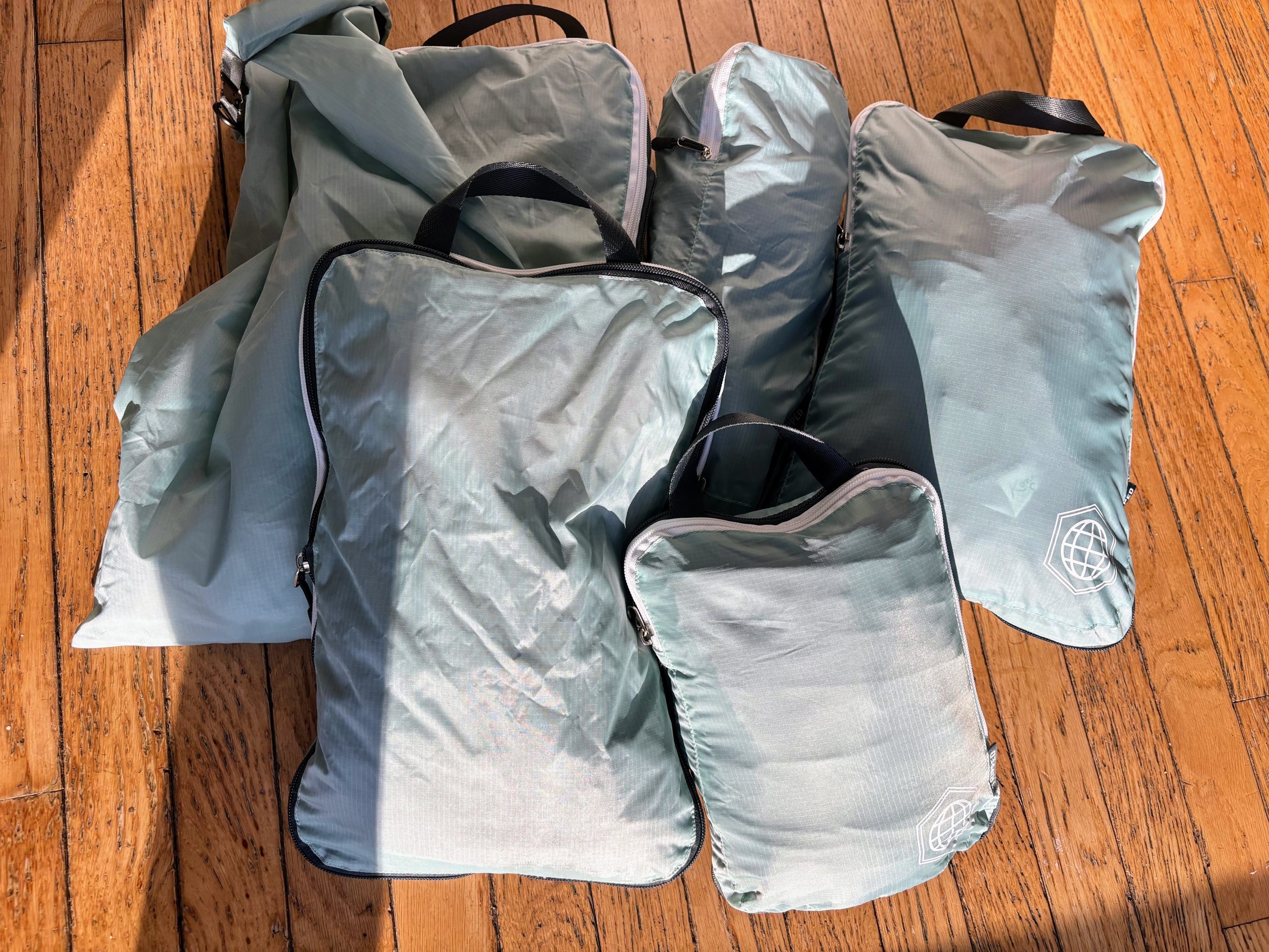 Six compression bags in light blue. The bags have zippers on top and zippers all of the way around, creating a compression system that makes your clothes more compact. 
