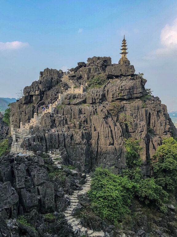 Narrow staircase slalom to pagoda atop rock, leading to serene panoramic views