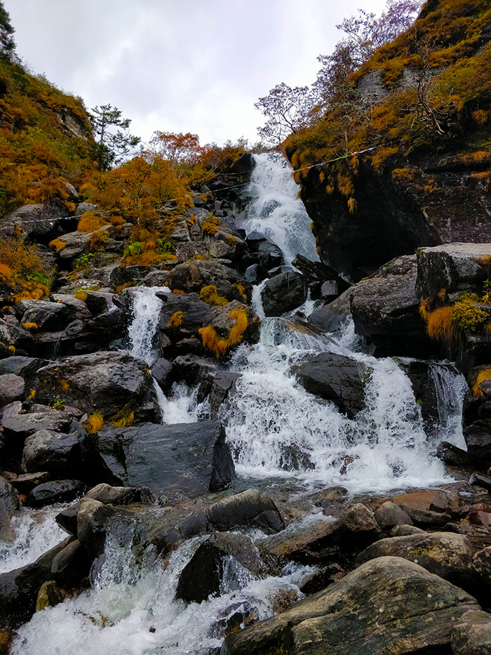 Waterfall near Baba Mandir Alt Text: Scenic waterfall cascading down the mountainside near Baba Mandir, providing a tranquil and refreshing sight for visitors amidst the natural beauty of Sikkim.