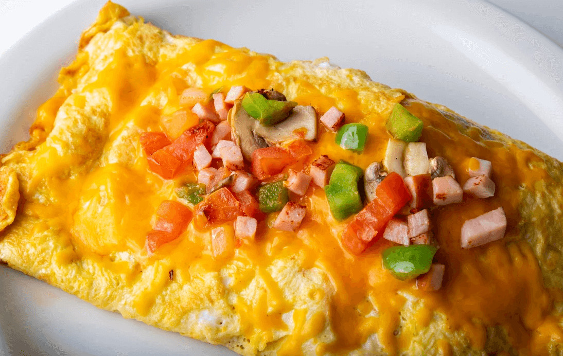 photo of an omelet topped with diced peppers and ham
