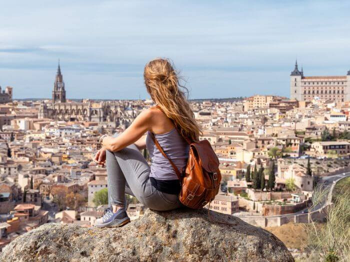 A woman sitting on a rock looking at Toledo, Spain