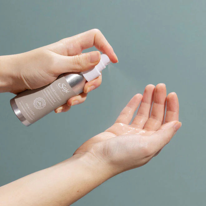 Woman using hand sanitizer spray for cleanliness during travel