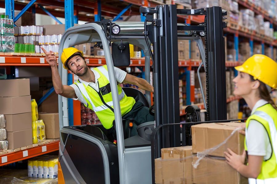 Forklift operator receiving training in a warehouse setting
